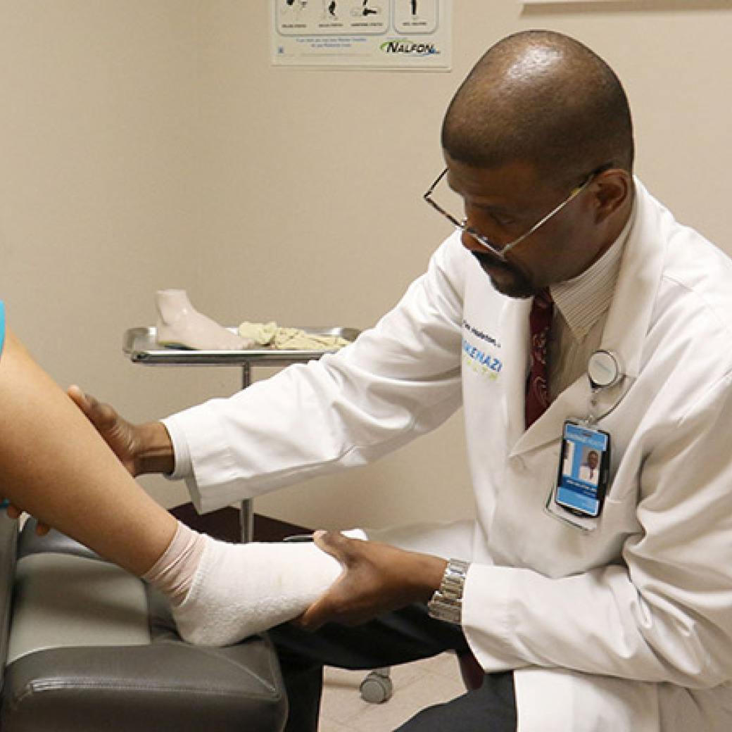 A podiatrist examining a patient's foot and lower leg in a clinical office