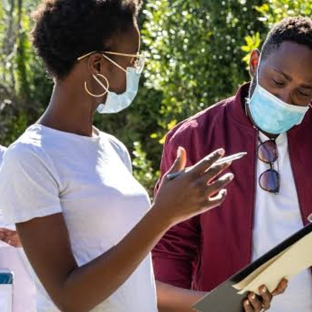 A diverse group of people wearing face masks while collaborating outdoors on a public health initiative