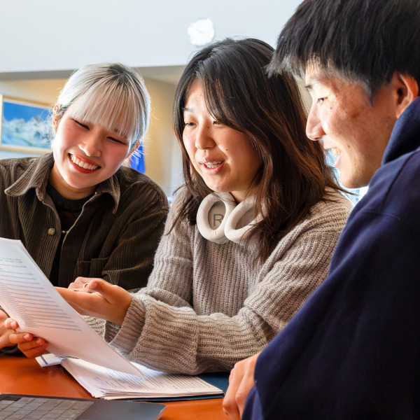 Three Social and Behavioral Sciences students look over a document together.
