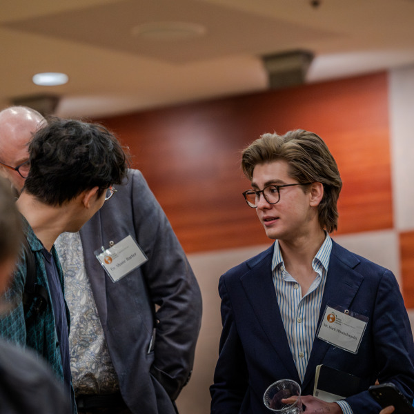 Attendees mingle amongst eachother while wearing formal attire.
