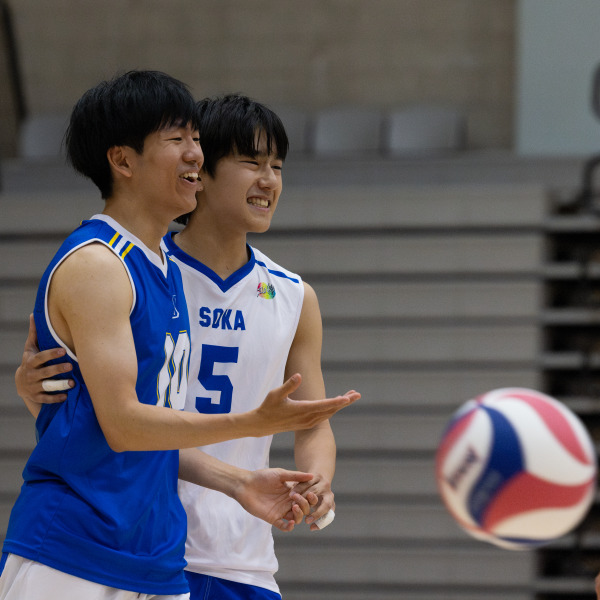 Two male volleyball players hug after a point.