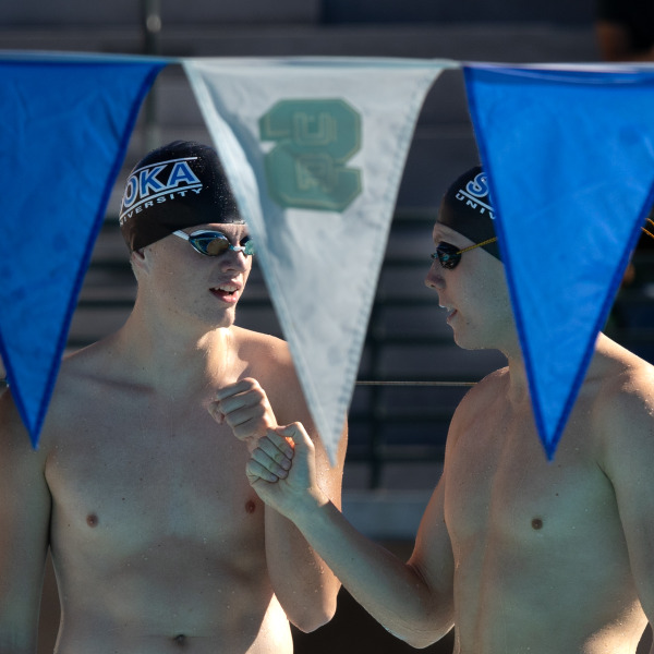 Two male swimmers fist bump after a race.