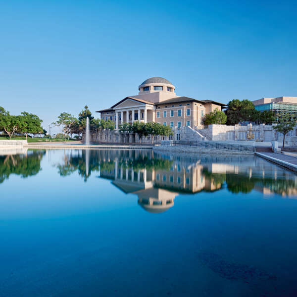 Founders Hall is across and reflecting into Peace Lake on a clear, blue sky day.
