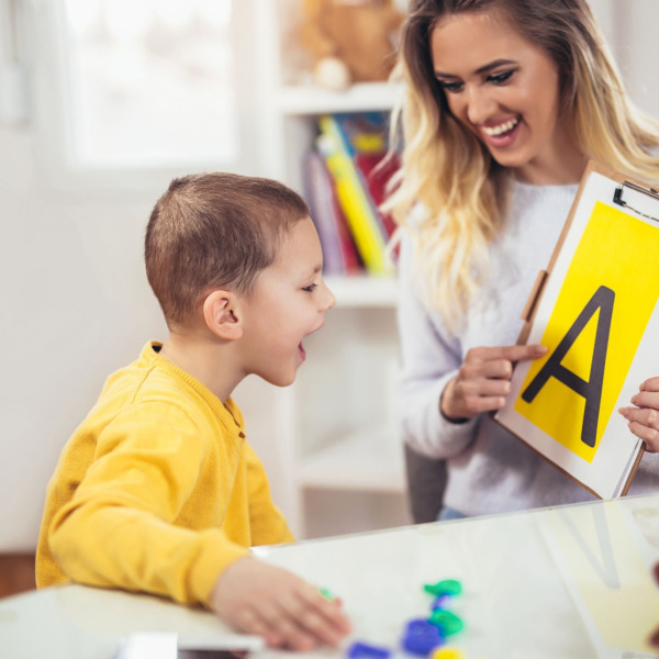 A speech-language pathologist helping a kid to spell letter "A"