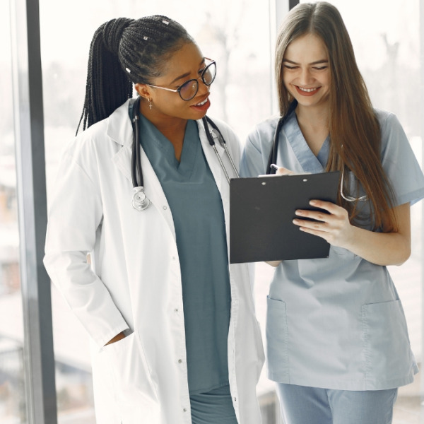 Physician smiling and standing next to a woman, who is holding a record