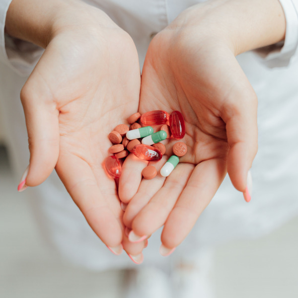 Close-up of a person holding various pills and capsules in their hands