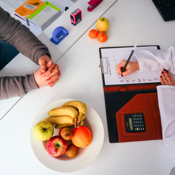 Doctor planning a healthy diet with fresh fruits on the table