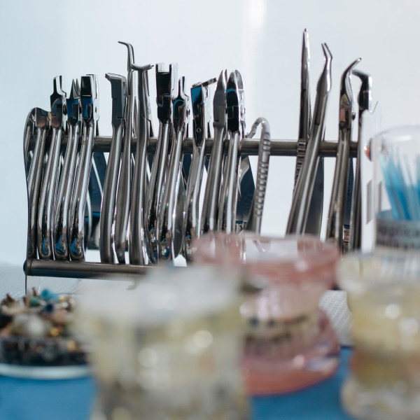 A set of stainless steel dental tools displayed on a blue surface in a clinic setting