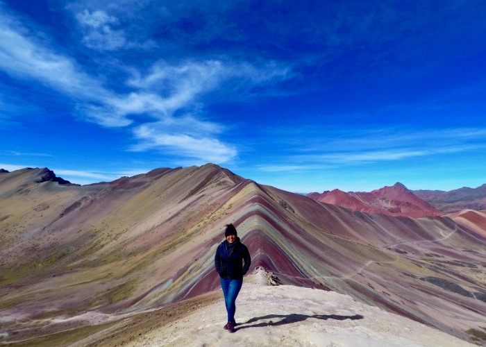 Delali standing in front of Spring Rainbow Mountain in Ecuador