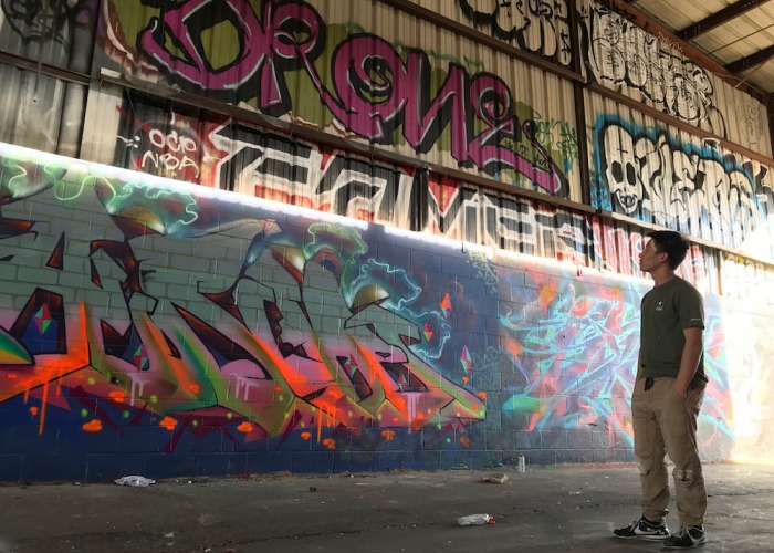 Soka University student looking up at wall of graffiti