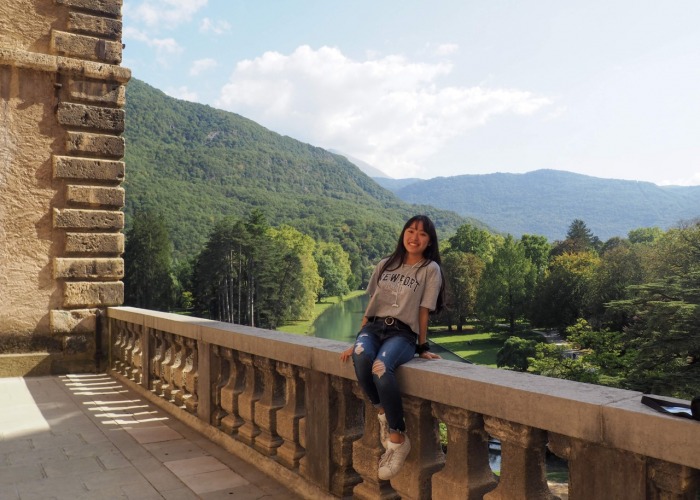 student sitting on ledge with green hills in background