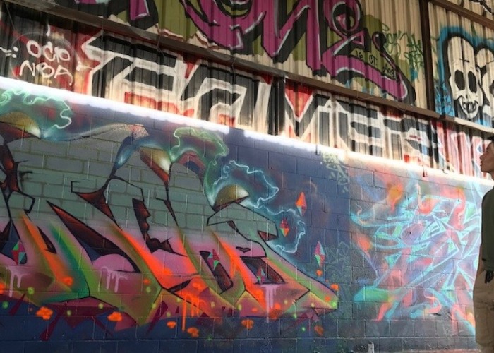 Soka University student looking up at wall of graffiti