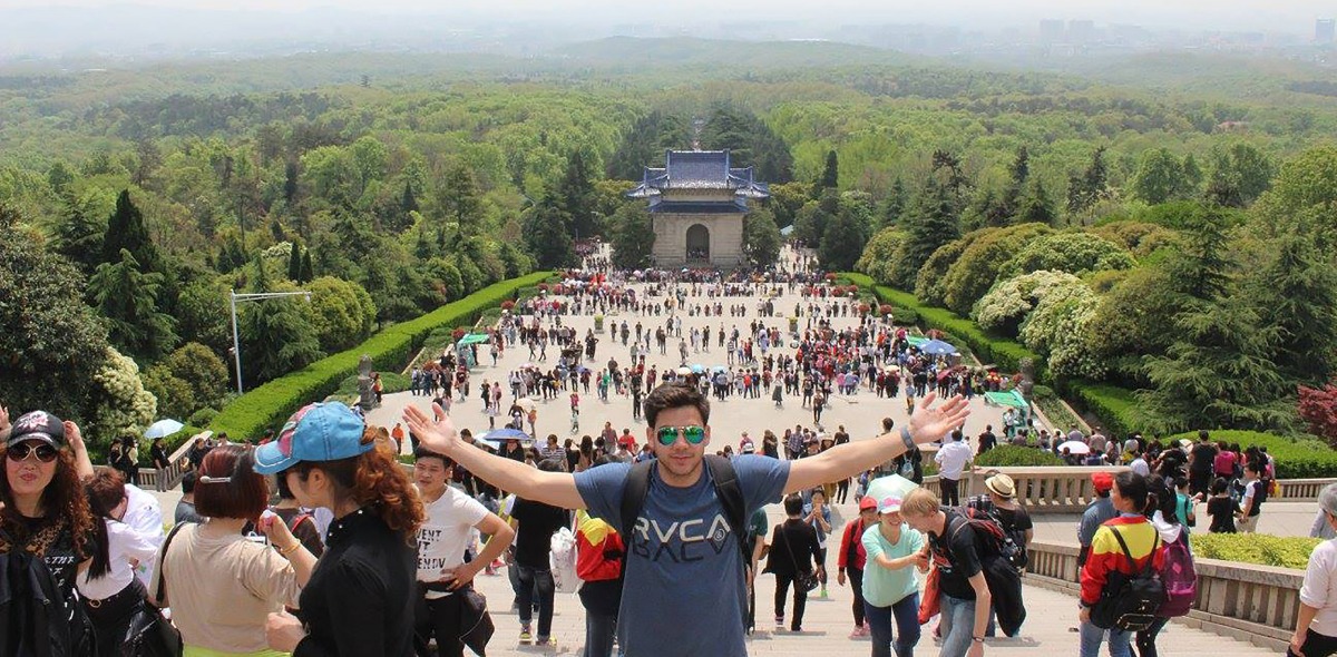 Student in front of buildings and nature in China.