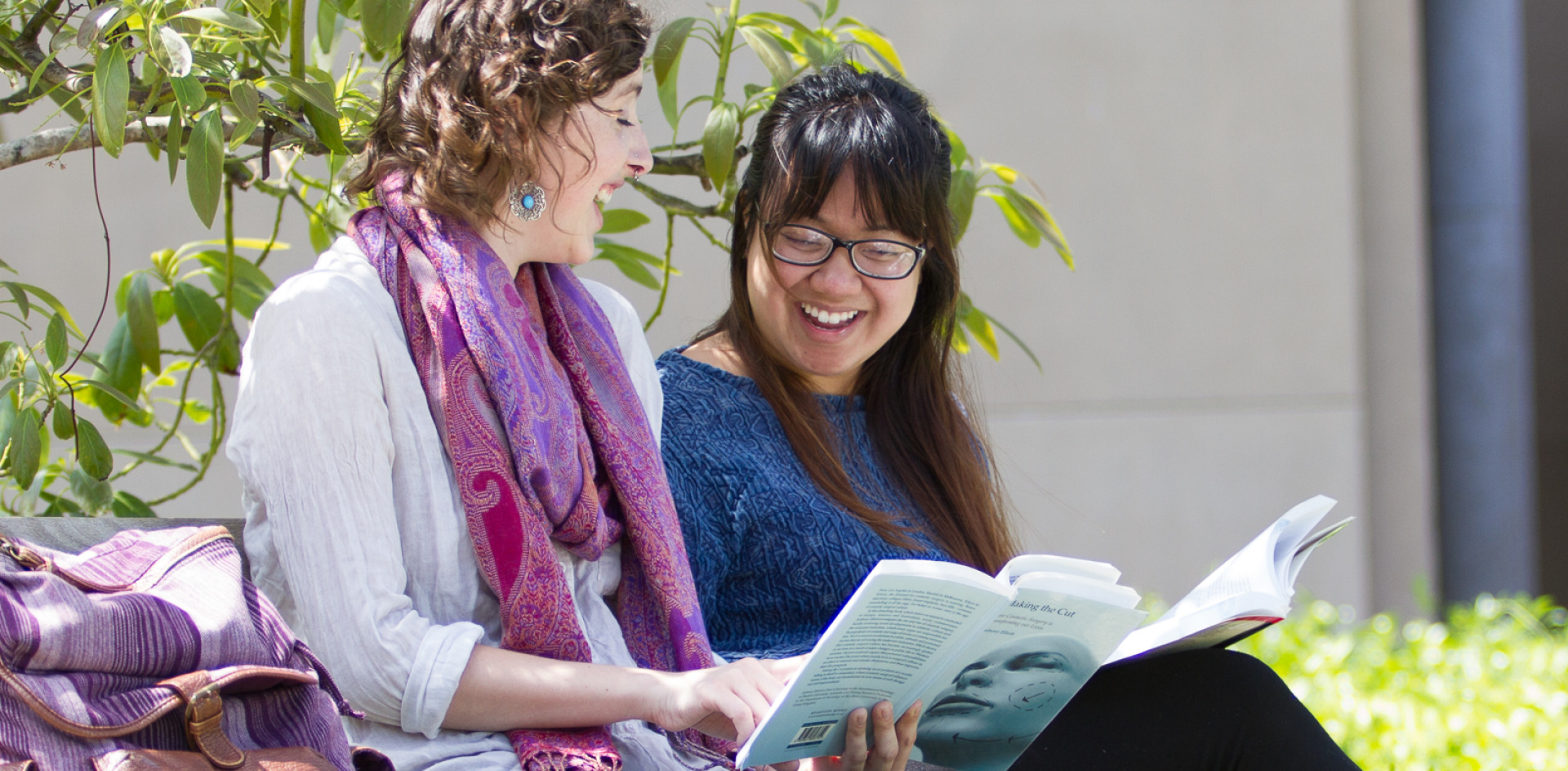 Students smiling and sharing a book