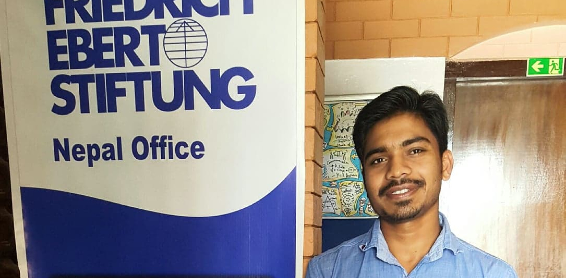 A student standing by a sign. 