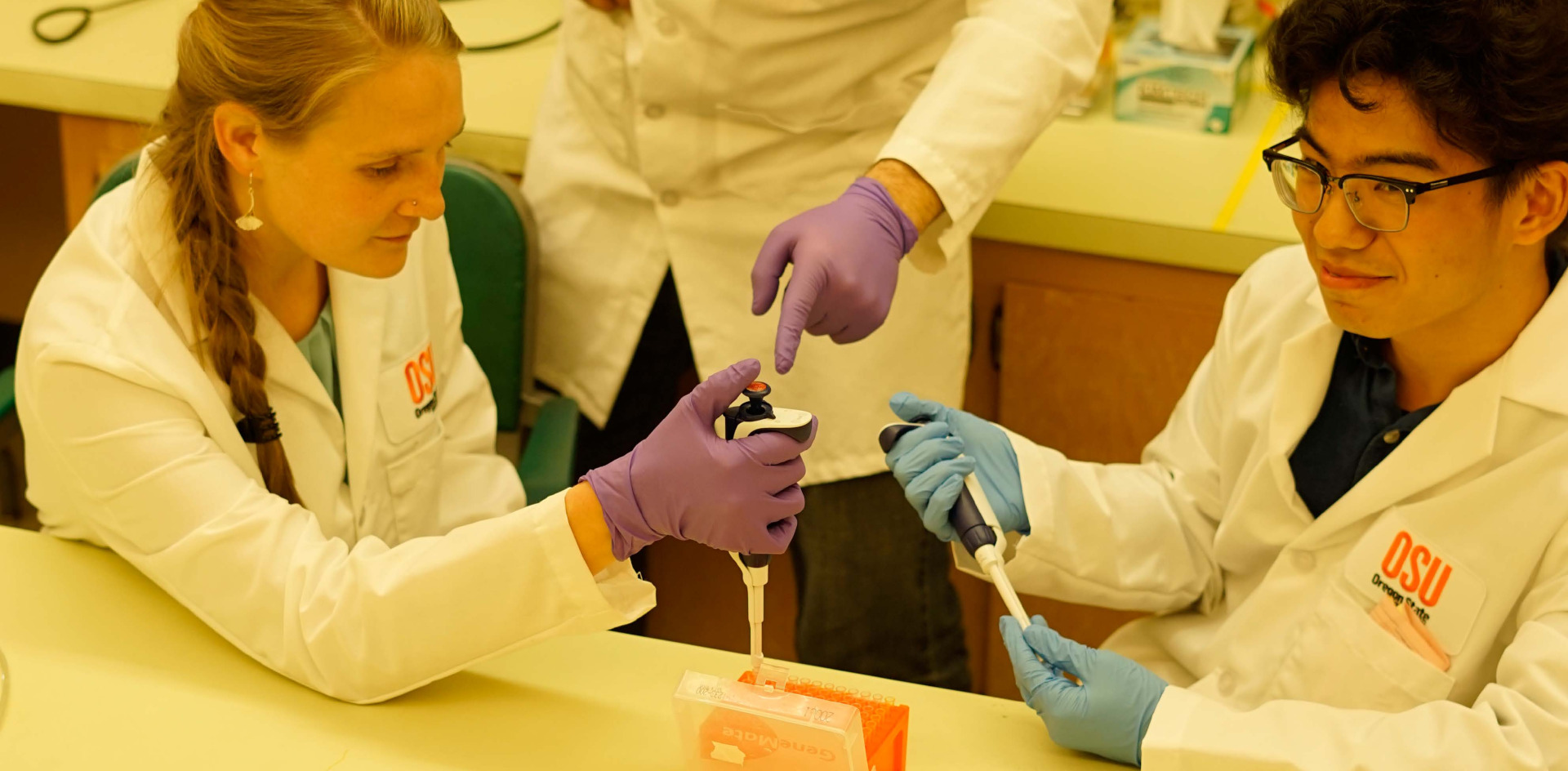 Two students with a professor in a lab. 