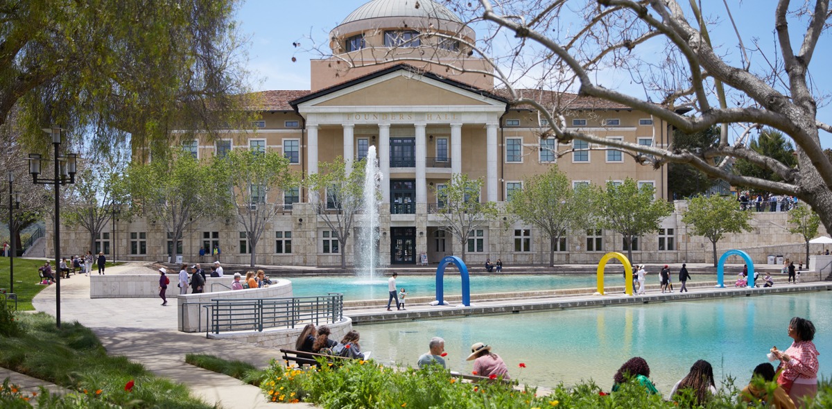 Visitors are walking around the SUA campus, going on the pathways through Peace Lake and in front of Founders Hall