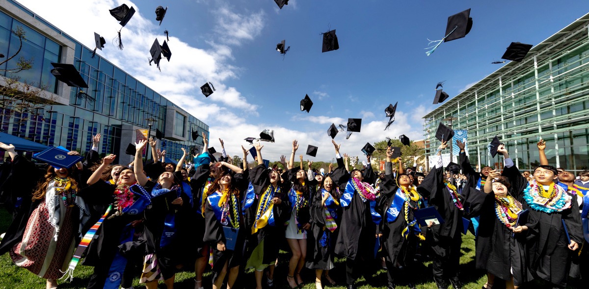 Graduating students toss their caps in the air celebrating commencement on SUA's campus.