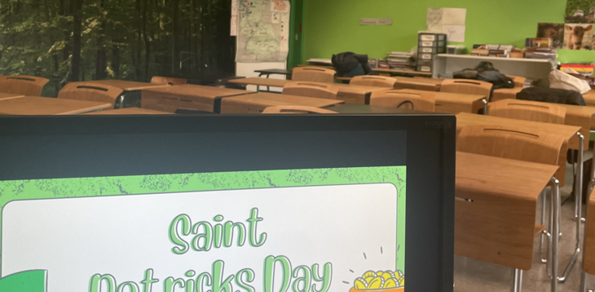 A sign reading "Saint Patricks Day in the US" is displayed at the entrance of a classroom with desks