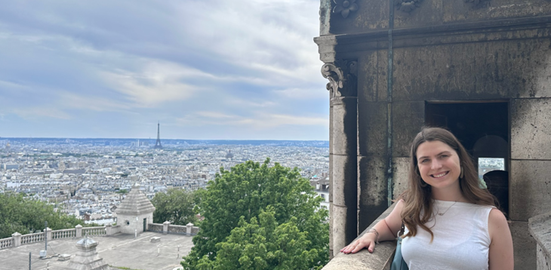 A girl poses at an overlook with the Eiffel Tower in the distance