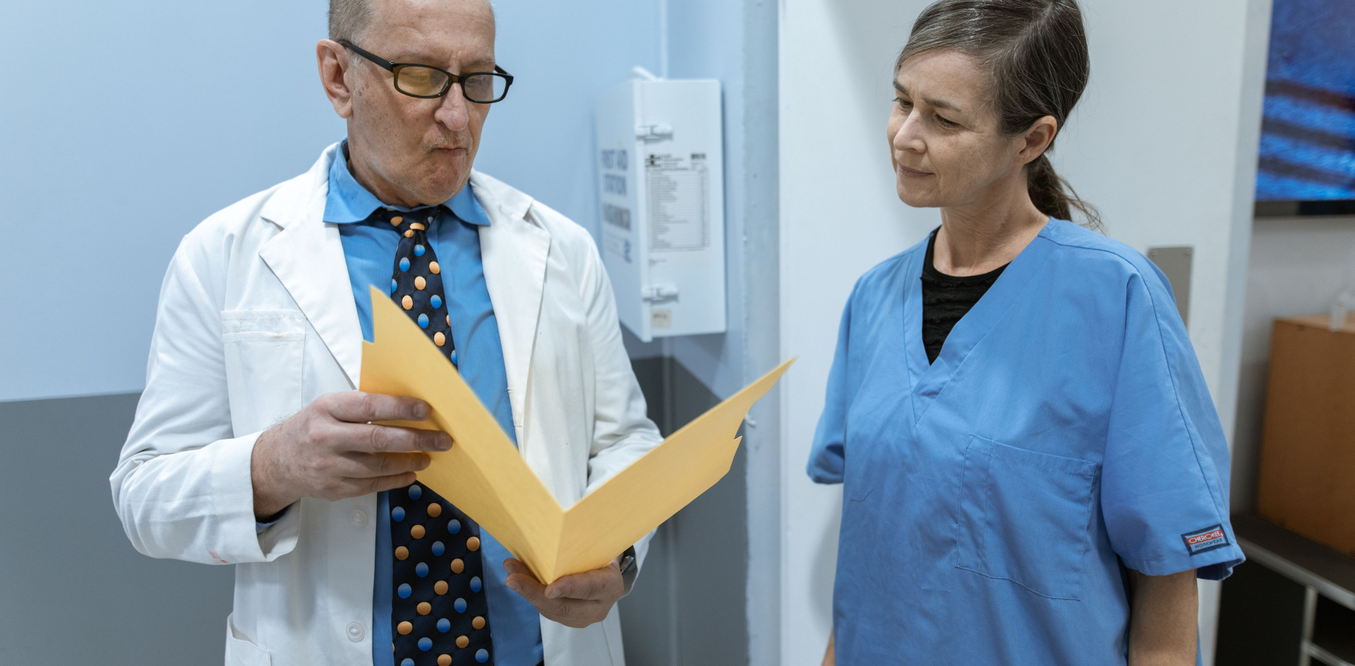 Doctors and PA in consultation over patient records within a hospital setting