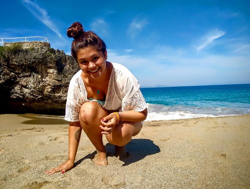 Student squatting in front of ocean