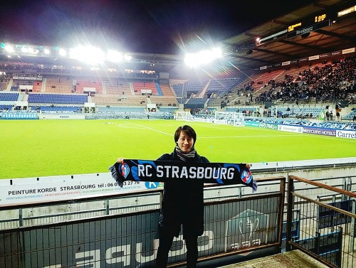 Student in front of football green with Strasbourg banner