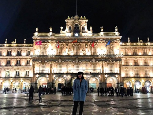 Student stands in front of lit up building in Salamanca