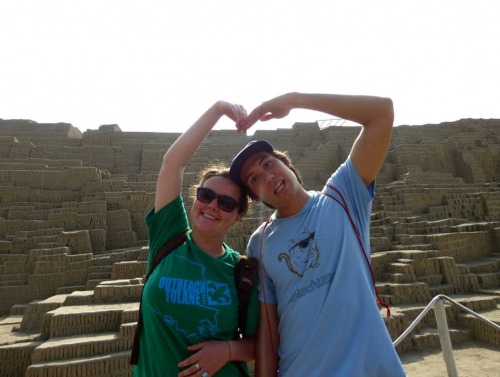 Students forming heart with their hands in front of ruin