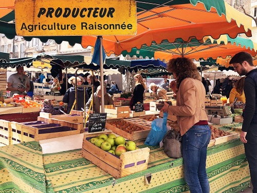 Women purchasing produce at a market in France