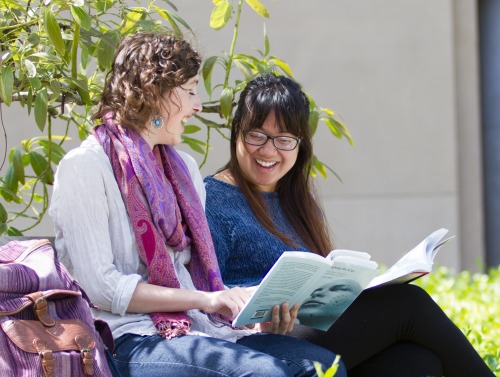 Students smiling and sharing a book