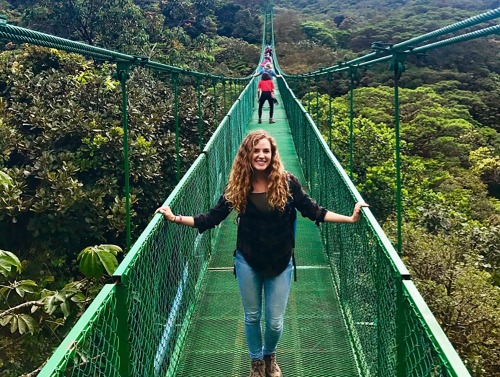 Student on bridge over green valley
