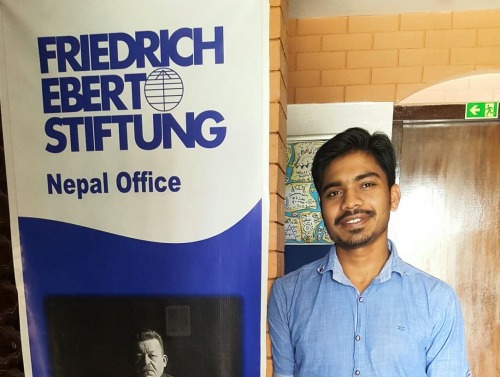 A student standing by a sign. 