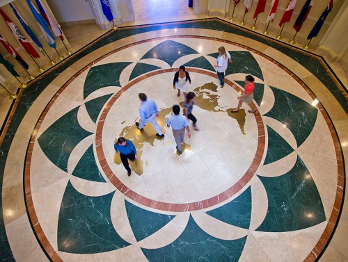 Students mingle on map of globe on the floor of Founders Hall