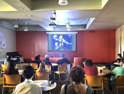 Nuclear Politics Summer Program participants watch a film on a projector screen.