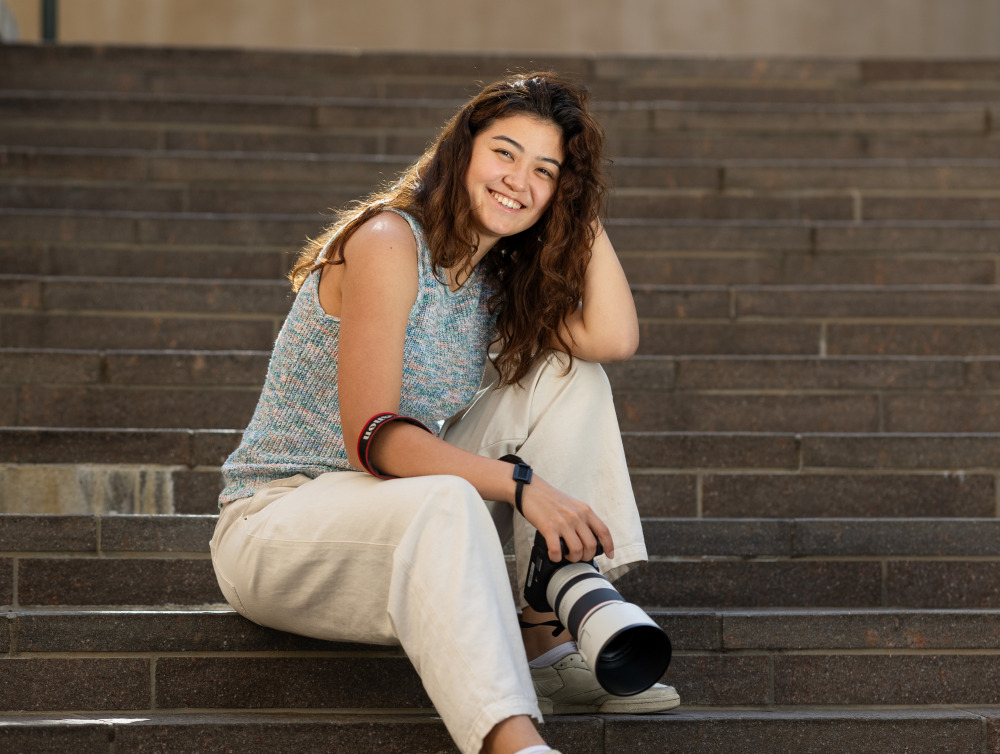 Marina Inoue poses with a camera on SUA's campus