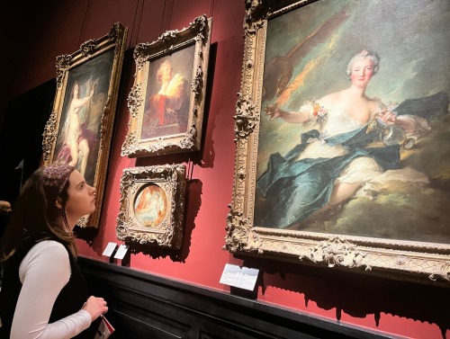 A girl looks at a painting in an art museum