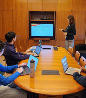 Librarian Jenn Tirrell leads a workshop in the Library with students sitting at a round table, looking at a screen.