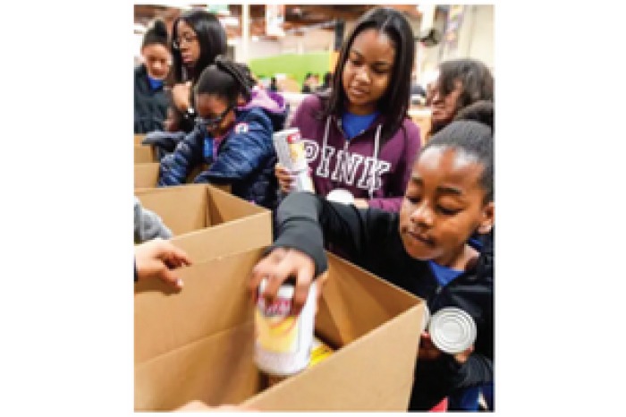 Children place donations into boxes while volunteering at a foodbank.