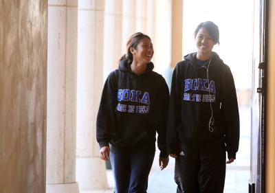 Two students walking wearing Soka sweatshirts