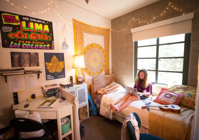 Girl sitting on bed in residence hall dorm room