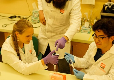 Two students with a professor in a lab.