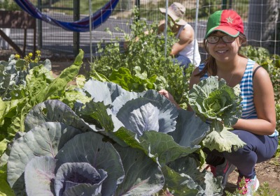 Image of a student posing with greens grown in the SIG.