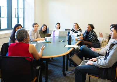 Image of students and a speaker sitting at a table.