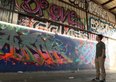 Soka University student looking up at wall of graffiti