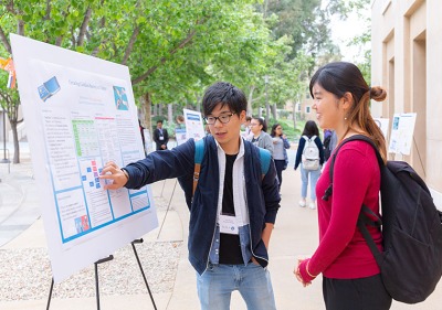 Students discuss findings at an easel displaying a poster