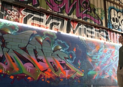 Soka University student looking up at wall of graffiti