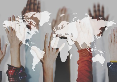 An aerial white outline of all the continents overlays diverse hands raised in the air