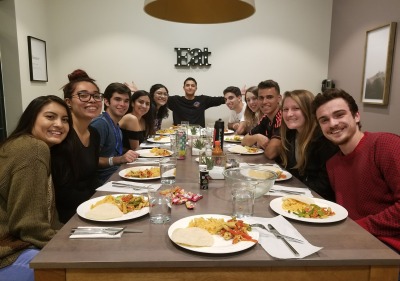 a group of students surrounding a table with food they prepared in the community kitchen
