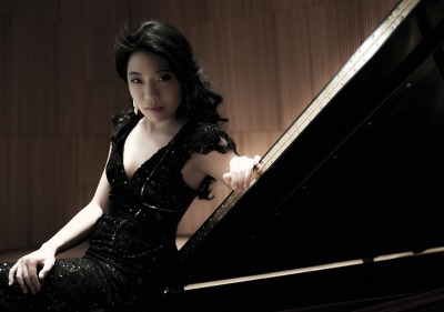Joyce Yang in black dress sitting at piano